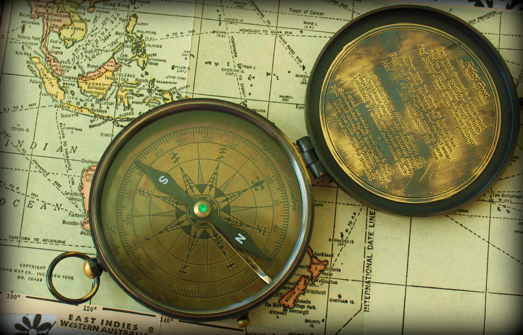 An old compass laying on a map, published as part of 