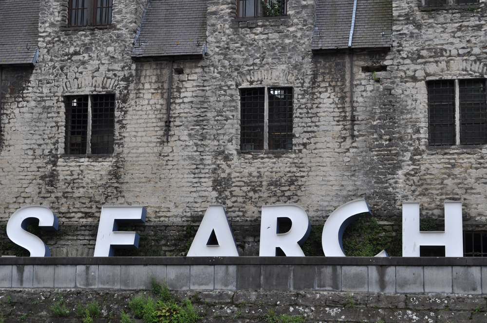 A fallen sign spelling out the word "search" next to an abandoned building, published as part of: "Being the Top Search Result on Google: Local vs National SEO"