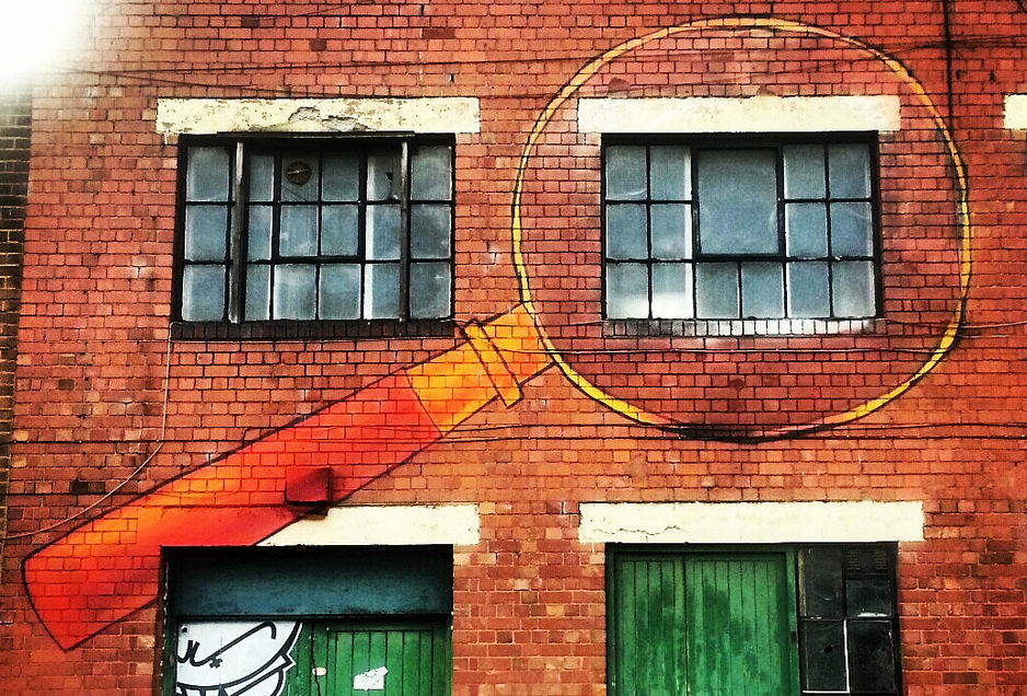 A magnifying glass painted on a brick building, published as part of 