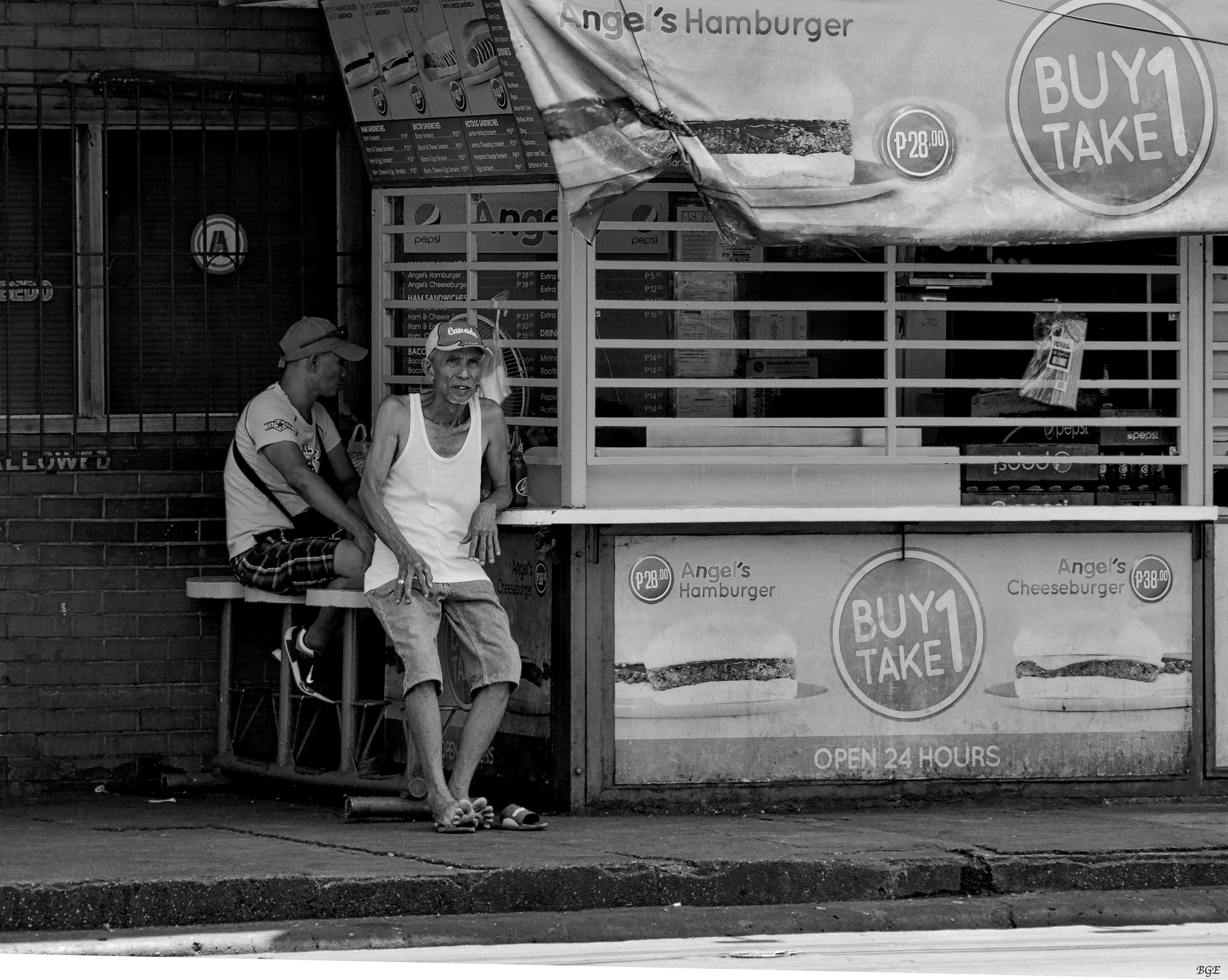 Two old men sitting by a hamburger stand on a street corner, published to 