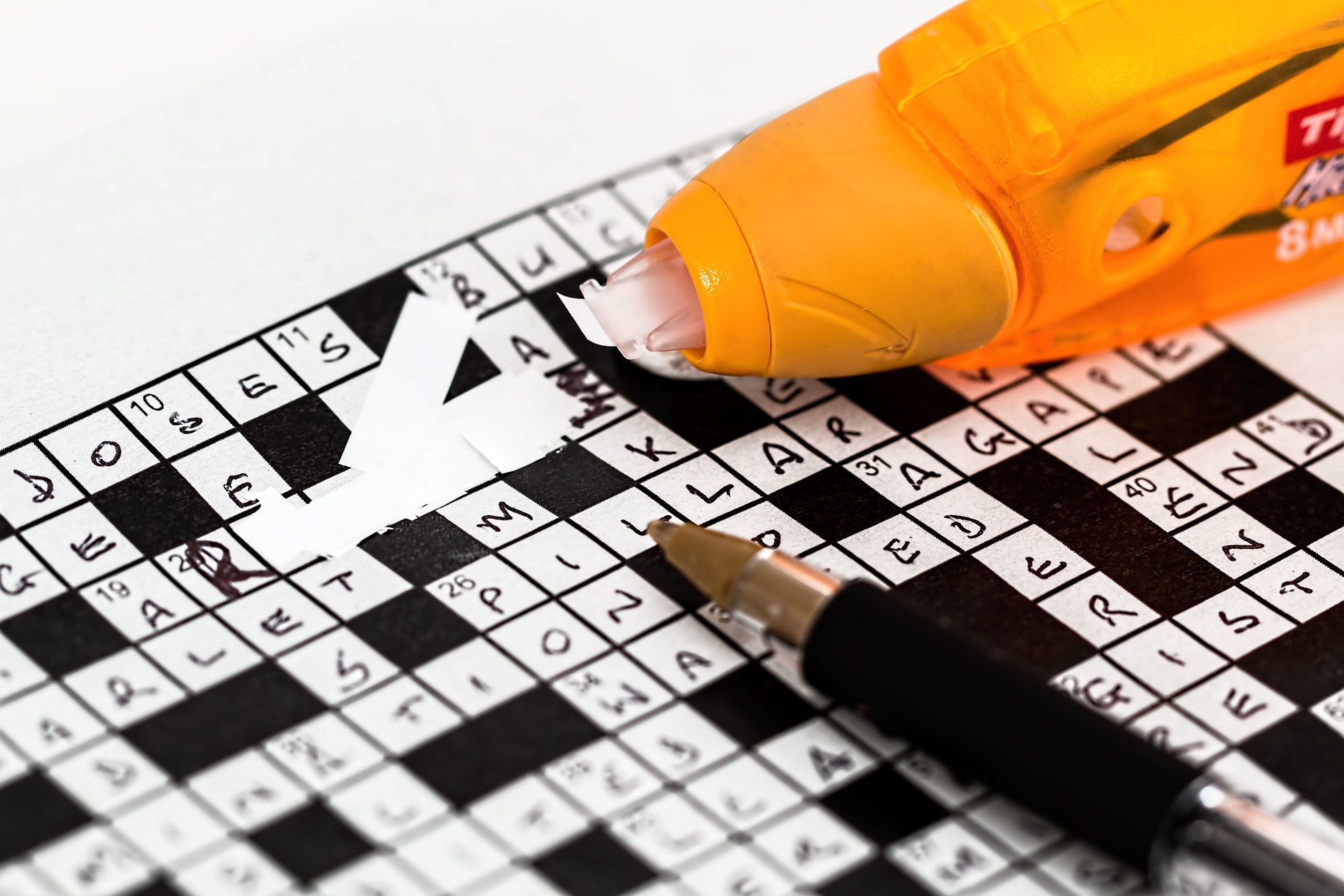 Someone whiting out a mistake in a crossword puzzle, published to: 